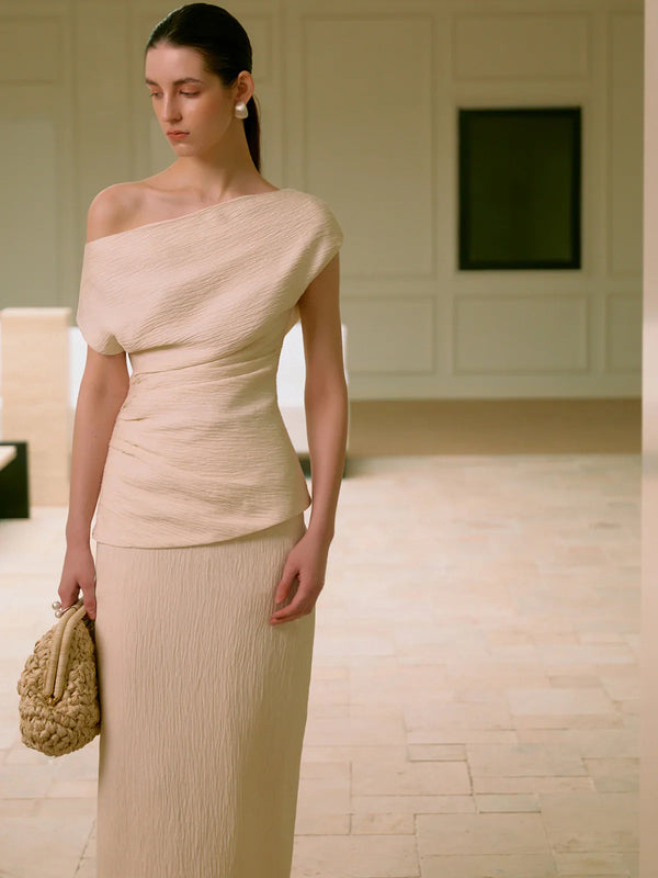 a woman in a beige dress holding a purse