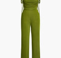 a woman wearing a green jumpsuit with a tie around the waist