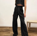 a woman wearing a black crop top and wide pants