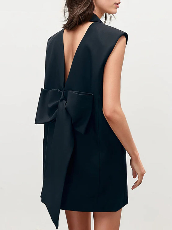 a woman wearing a black dress with a bow back