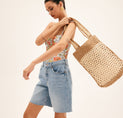 a woman in a floral top is carrying a woven bag
