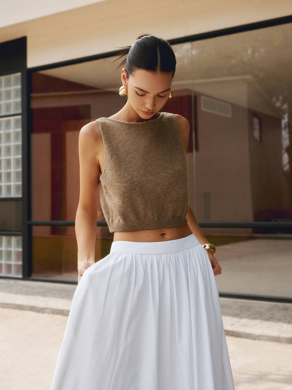 a woman in a white skirt and a brown sweater