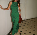 a woman in a green dress leaning against a wall