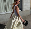a woman walking down the street in a white skirt