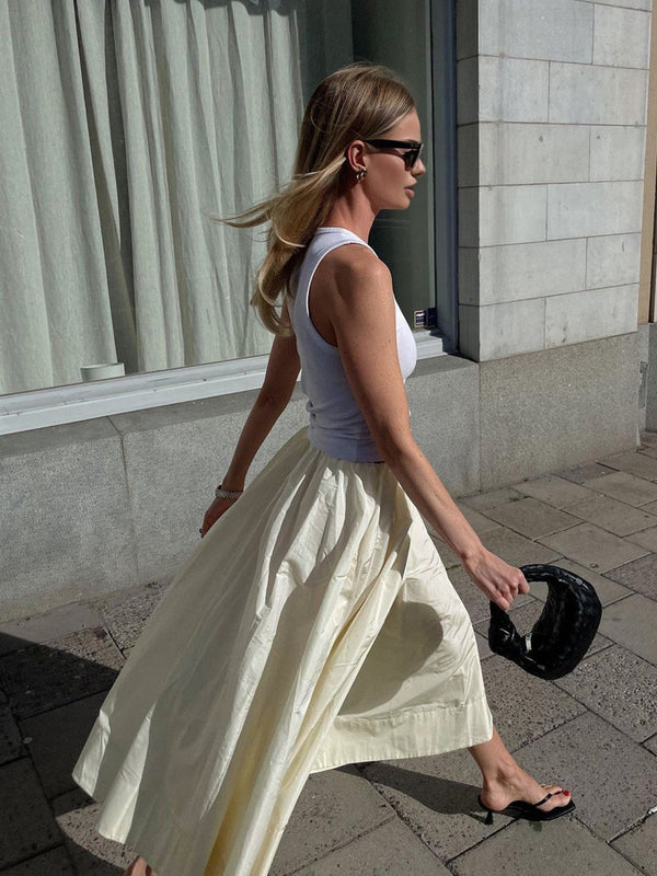 a woman walking down the street in a white skirt