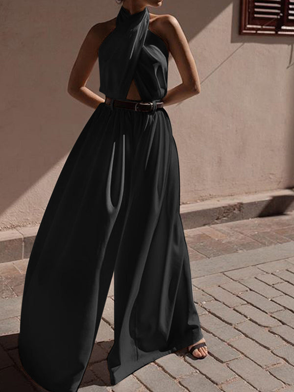 a woman in a black jumpsuit standing on a sidewalk