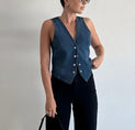 a woman in black pants and a denim vest