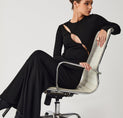 a woman in a black dress sitting on a white chair