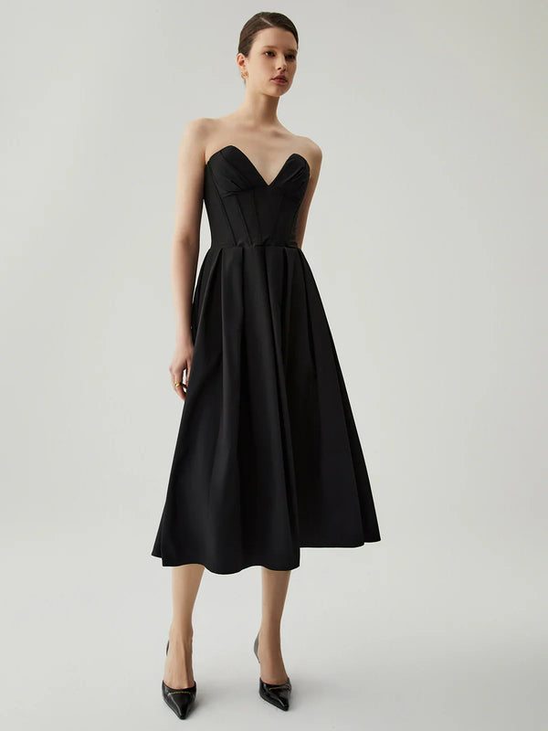 a woman wearing a black dress and heels