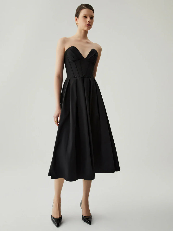 a woman wearing a black dress and heels