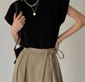 a woman in a black top and beige skirt