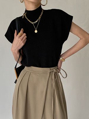 a woman in a black top and beige skirt
