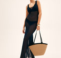 a woman in a black dress holding a straw bag