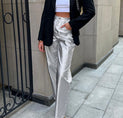 a woman wearing a white crop top and silver pants