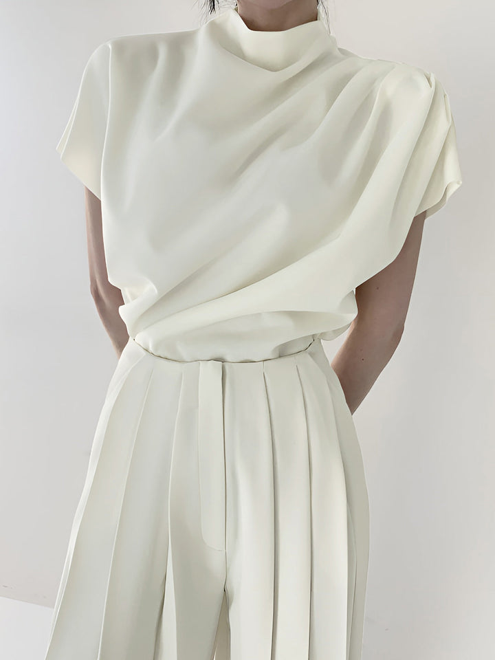 a woman wearing a white top and wide pants