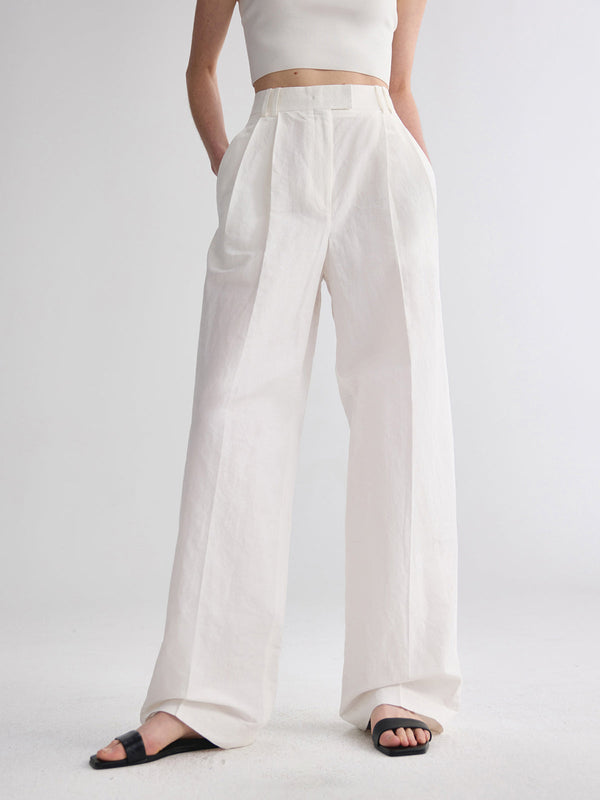 a woman wearing a white crop top and wide pants