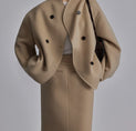 a woman in a beige coat and skirt