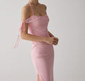 a woman wearing a pink dress with a side slit
