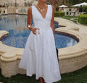 a woman in a white dress standing next to a pool