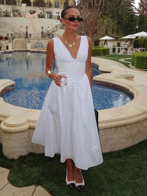 a woman in a white dress standing next to a pool