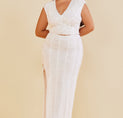 a woman in a white dress standing against a wall