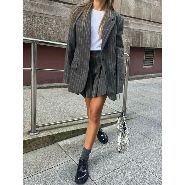 a woman wearing a black and white striped blaze jacket, white t shirt, black boots, and a white