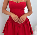 a woman in a red dress standing next to a teddy bear