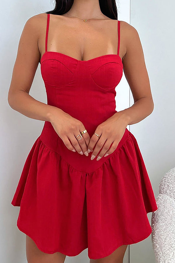 a woman in a red dress standing next to a teddy bear