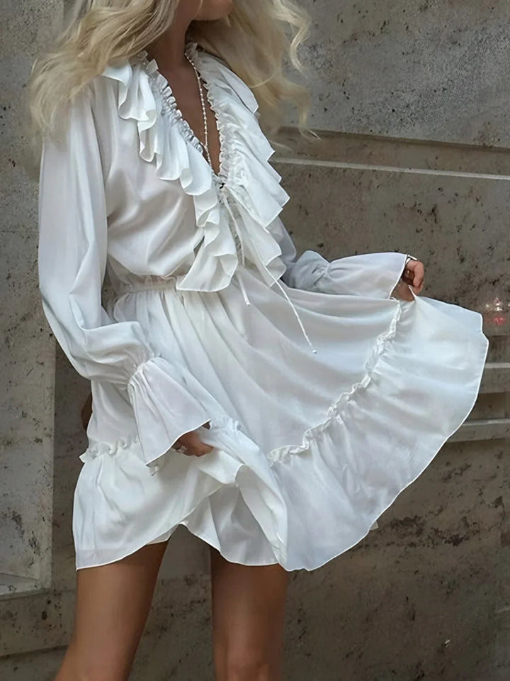 a woman in a white dress standing against a wall