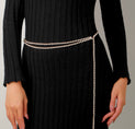 a woman in a black dress with a chain belt