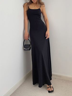 a woman in a black dress leaning against a wall