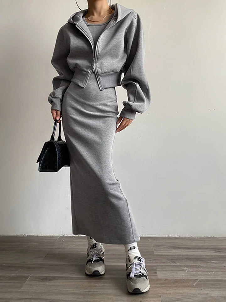 a woman wearing a grey dress and white sneakers