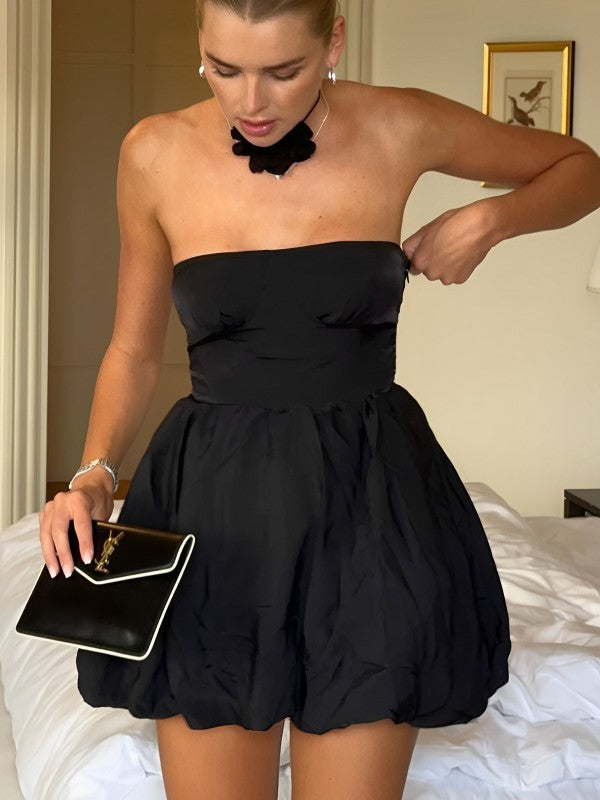 a woman in a black dress standing on a bed