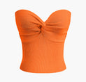a woman wearing an orange top with a large bow